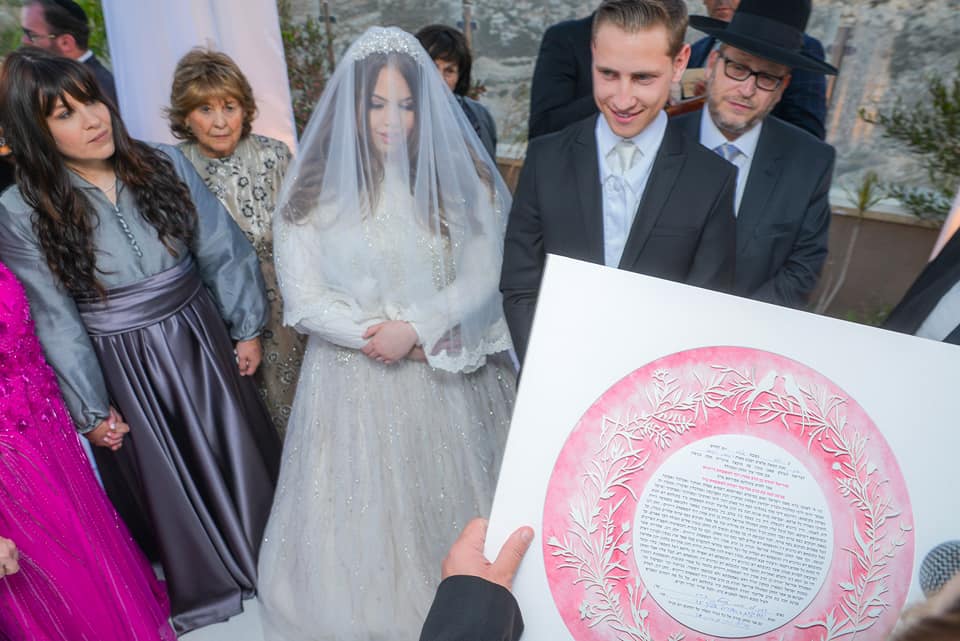 3. A heartwarming image of an interfaith family gathered around their Ketubah, symbolizing unity and mutual respect.